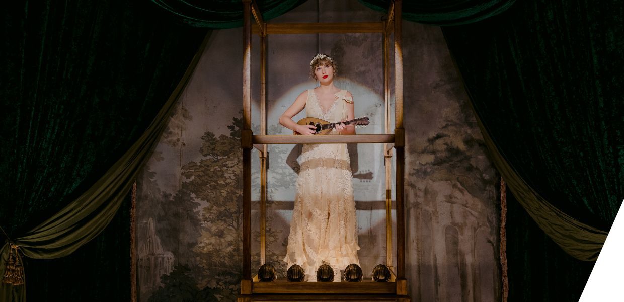 Taylor Swift stood in an illuminated glass box, playing a lute